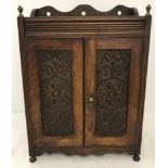 A small mahogany 2 door cupboard with carved panels to doors.