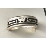 A men's silver spinner ring. Central moving section decorated with arrows and hearts.