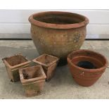 A large round terracotta garden planter together with 4 small terracotta plant pots.