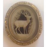 A vintage brooch with central carved panel of a deer.