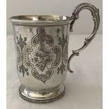 A Victorian silver christening mug with engraved detail, blank cartouche and decorative handle.