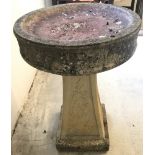 A concrete garden bird bath with decorative 4 sided pedestal.