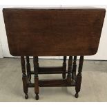 A vintage small dark wood drop leaf, gate leg table with turned legs.