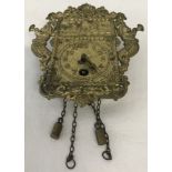 A miniature wall hanging clock with chains and weights and brass face.