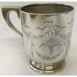 A hallmarked silver christening mug with engraved floral basket and swag decoration.