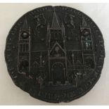 A reproduction antique seal depicting a cathedral cast in metal.