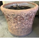 A large round terracotta garden planter with decorative sides.