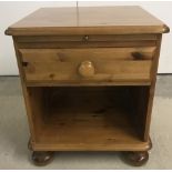 A modern pine bedside cabinet with single drawer and under storage, on bun feet.
