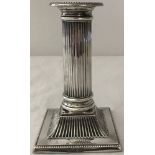 An antique silver candlestick of classical fluted design with weighted base.