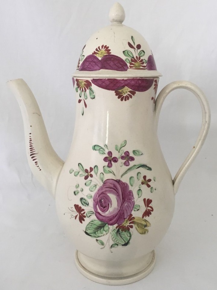 A circa 1790 cream ware coffee pot with purple flower decoration.