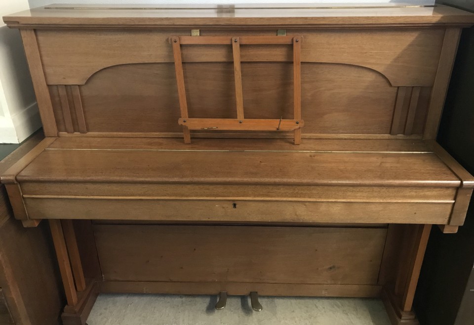 A modern light oak finish upright piano.