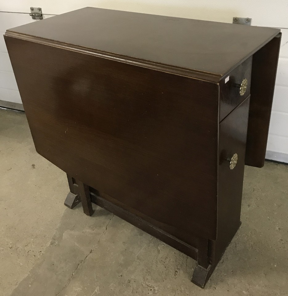 A vintage dark wood drop leaf gate leg table with cupboards to ends.