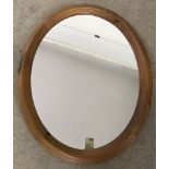 A modern pine framed oval wall hanging mirror.