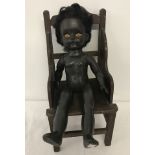 An English made black vinyl doll together with a dolls wooden chair.