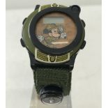 A Mickey Mouse " Safari Adventures " digital watch with green woven fabric strap.