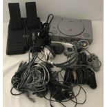 A Sony Playstation console together with 2 wired controls, leads, headphones and foot pedal.