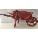A vintage wooden 2 handled red and gold painted wheel barrow.