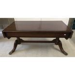 A modern dark wood coffee table with drop leaf ends and brass claw feet.