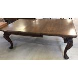 A large mahogany wind out dining table on cabriole shaped legs with carved decoration.