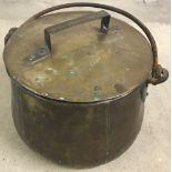 A large, heavy brass lidded cauldron with handle and lid.