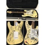 A cased Fender Stratocaster MZI185328 2002 V Festival guitar. Signed by performing artists.