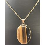 An oval shaped Tigers Eye pendant set into 9ct gold, mounted on a 9ct gold rope chain.