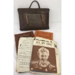 A vintage leather music satchel containing vintage sheet music and books.