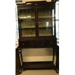 A mahogany 2 door display cabinet with leaded glass doors and 2 interior fabric lined shelves.