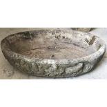 A large oval shaped concrete garden planter with decoration to sides.