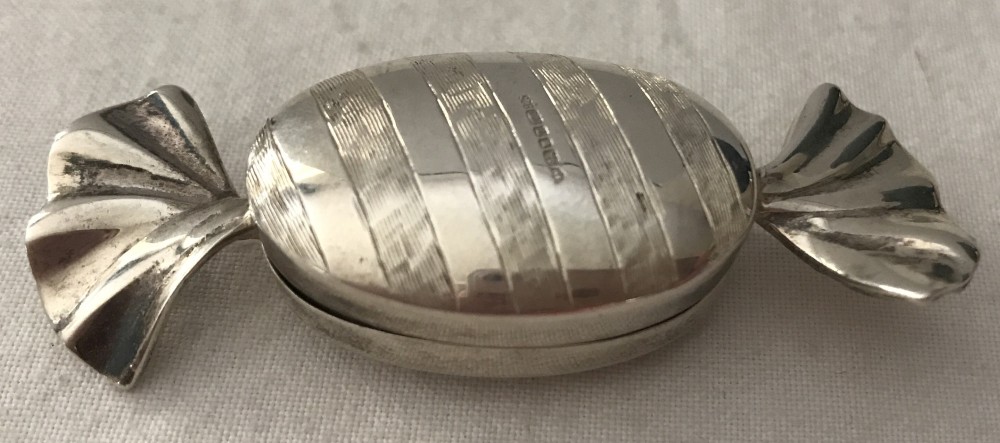 A silver pill boxed shaped like a wrapped sweet. Hallmarked London 1993.