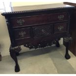 A reproduction mahogany coloured 4 drawer chest with carved decoration.