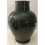 A large ceramic vase with green glaze and metal rim to top and bottom.