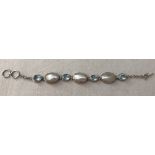 A 925 silver bracelet set with blue topaz stones and mother of pearl.