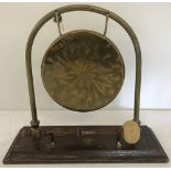 A vintage brass gong on wooden plinth with mallet.