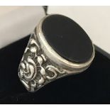 A men's silver and onyx signet ring with decorative detail to shoulders.