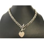 A heavy decorative silver necklace with t bar fastening and heart pendant.