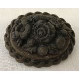 A bog oak Victorian brooch decorated with carved flowers.