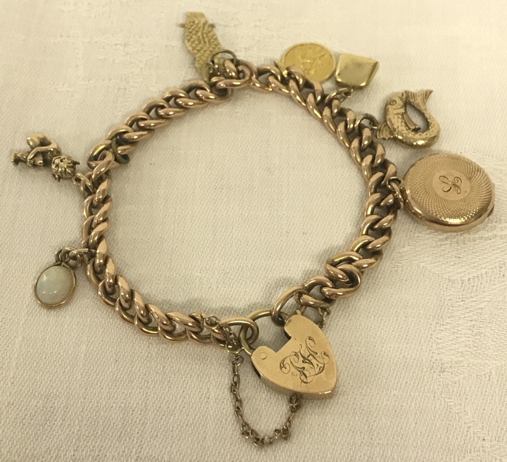 A 9ct gold charm bracelet with heart shaped padlock and 7 charms.