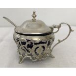 A 3 footed decorative silver mustard pot with blue glass liner and silver mustard spoon.