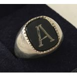 A silver and onyx signet ring engraved with the letter A.