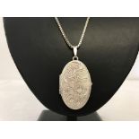 A large vintage oval locket with flower engraving to front on a 20 inch silver box chain.