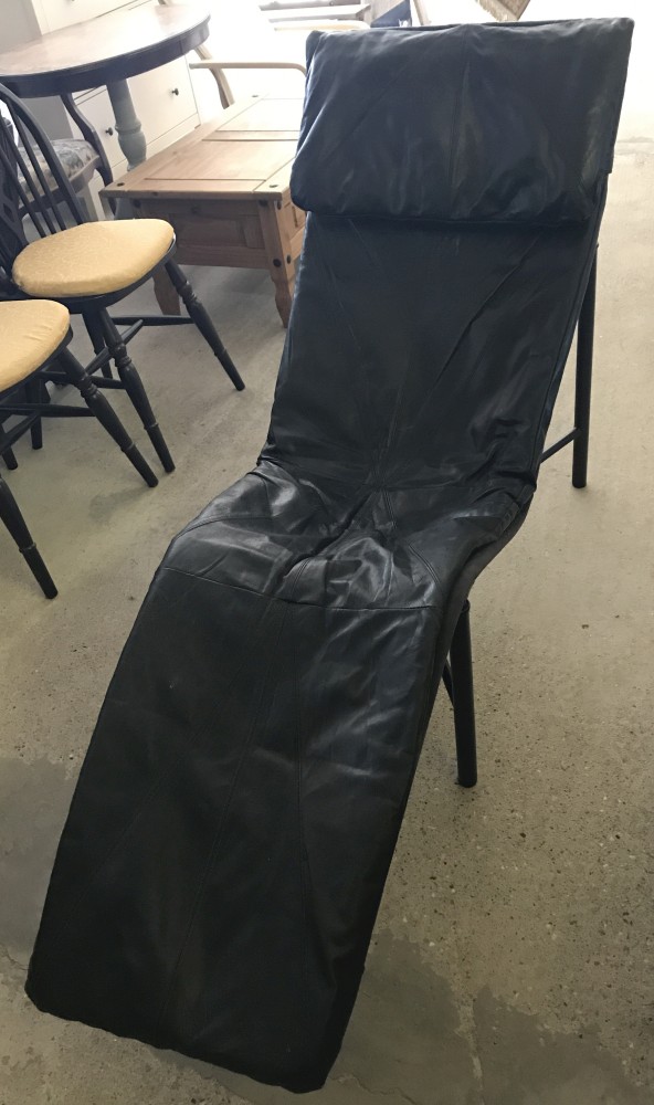 A modern black leather covered lounger chair.