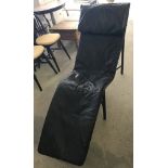 A modern black leather covered lounger chair.