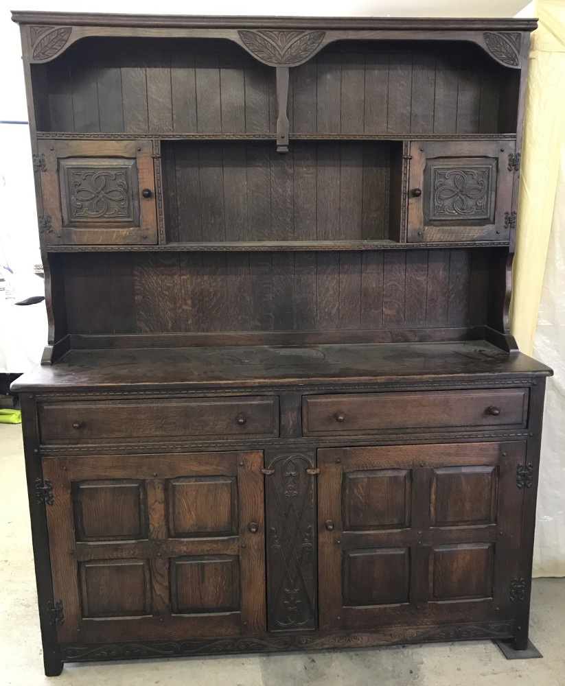A dark oak 2 door, 2 drawer dresser with shelving a small cupboards to top.