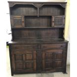 A dark oak 2 door, 2 drawer dresser with shelving a small cupboards to top.