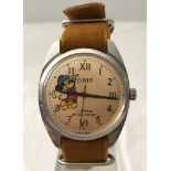 A Mickey Mouse playing golf wristwatch by Oris on mustard fabric strap.