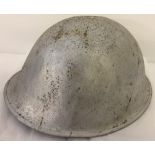 A silver coloured tin helmet complete with liner and canvas strap.