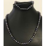 A peacock blue pearl necklace with white metal clasp.