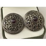 A pair of large round silver earrings set with central cabochon garnets.