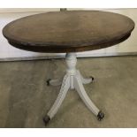 A vintage oval topped pedestal occasional table with metal claw feet and castors.